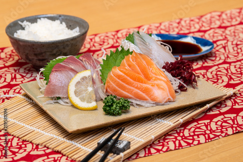 sashimi set on a plate with rice and soy sauce and chopsticks