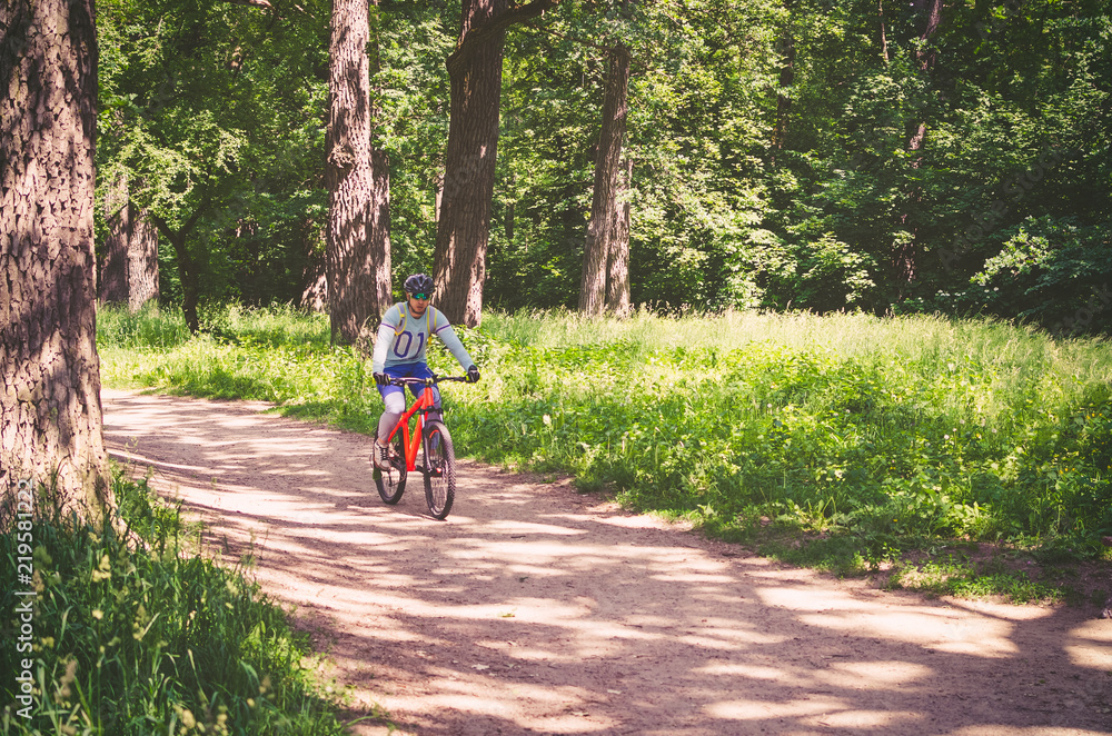 Obraz premium Cyclist in helmet on orange bike riding in park