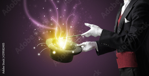 Magician hand conjure with wand  light from a black cylinder © ra2 studio