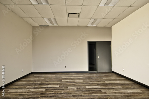 Interior of empty office room  wooden floor  beige walls and grey door.