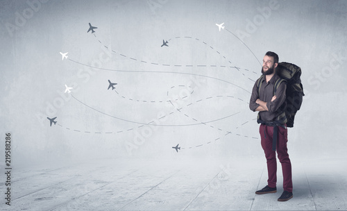 Handsome young man standing with a backpack on his back and little planes in the background