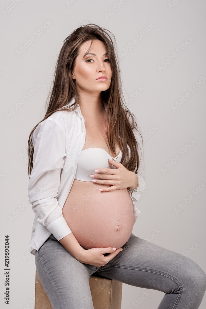 Pregnant woman touches her belly with hands on white background Pregnant woman touches her belly with hands on white background
