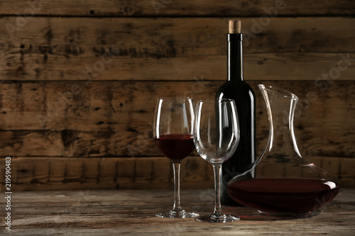 Glassware and bottle with red wine on wooden table