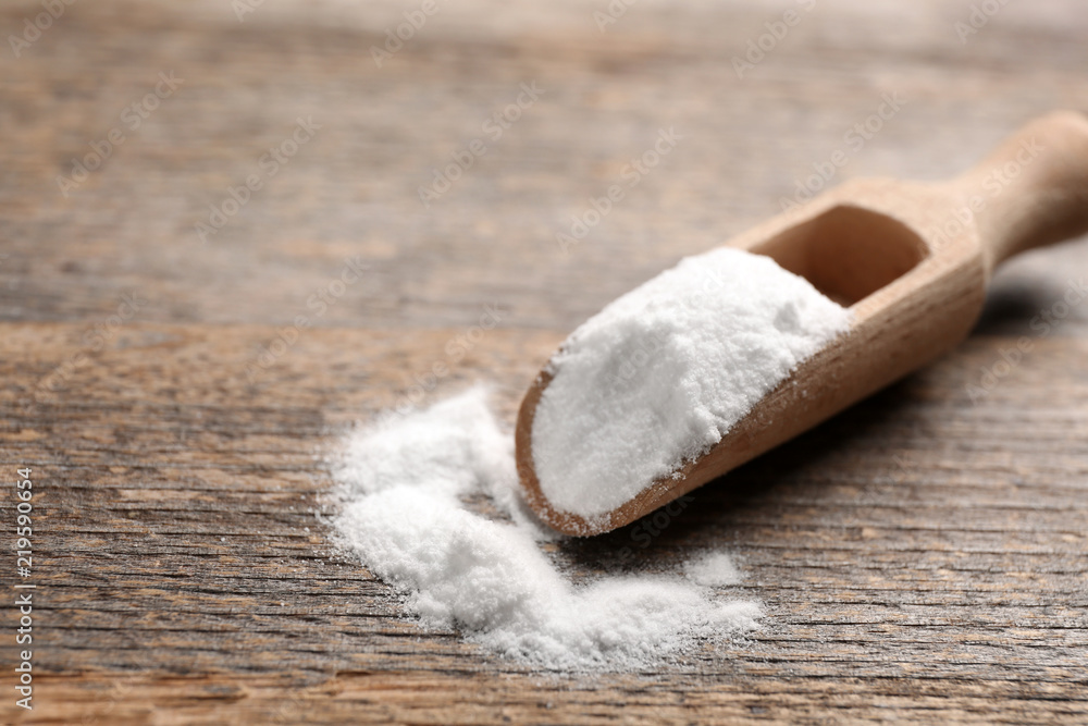 Scoop with baking soda on wooden table Scoop with baking soda on wooden table