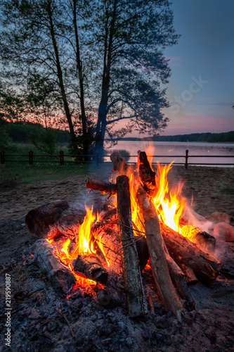 Stunning bonfire at dusk by the lake in summer