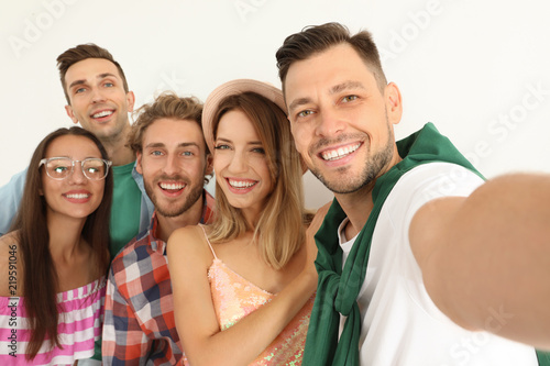 Group of happy young people taking selfie on white background