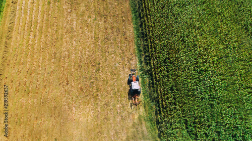 Harvest of hay  tractor using rotary rakes on agriculture crops. Aerial view  dron view