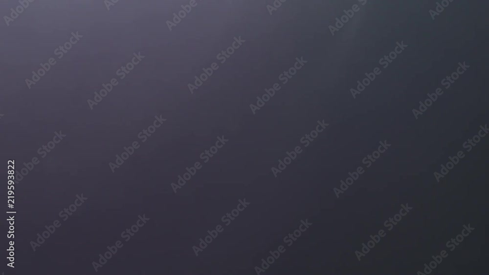 Slow motion backlit dust particles floating in the air on a black background with lens flare Slow motion backlit dust particles floating in the air on a black background with lens flare