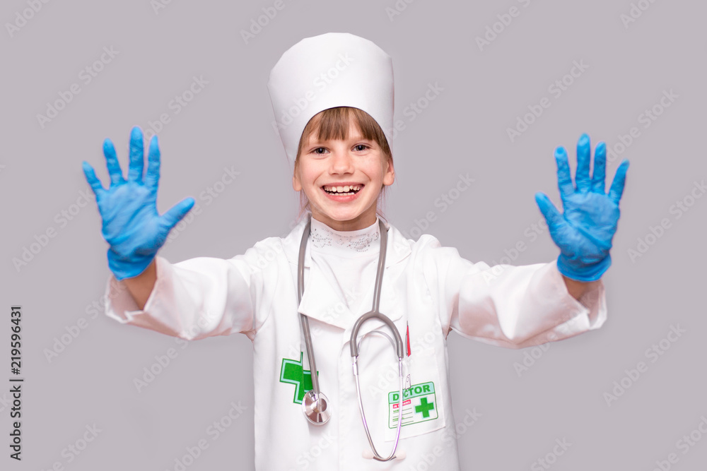 Smiling little girl in medical uniform and blue gloves looking at camera isolated on white Smiling little girl in medical uniform and blue gloves looking at camera isolated on white