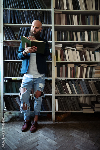Full length portrait of stylish bearded man reading book