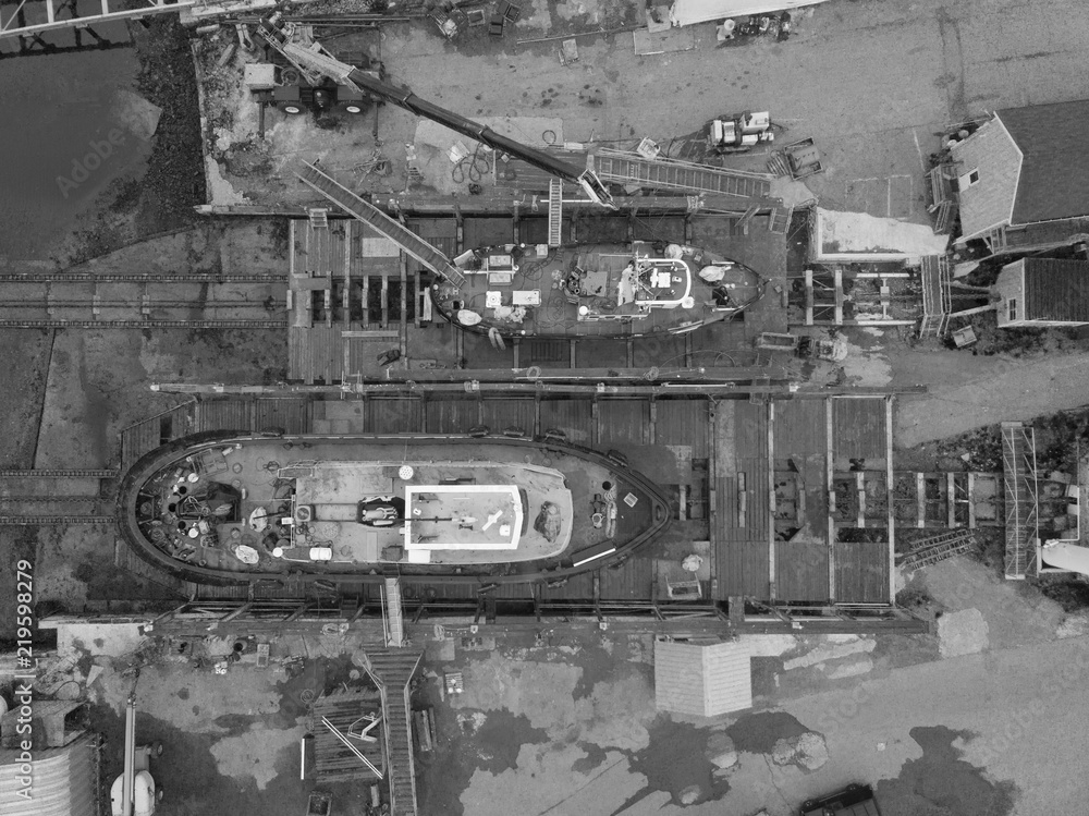 Fototapeta premium Two Tug boats sit in drydock in Rockland Maine as seen from an aerial drone image