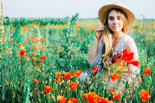 Young countryside girl sitting in the field of poppies © different_nata