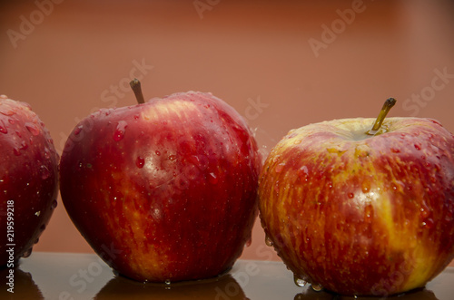 Tres manzanas mojadas sobre fondo rojo photo