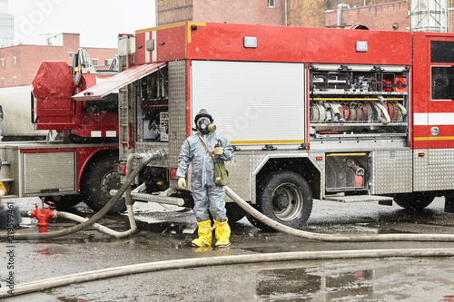 The employee of service of rescue about the fire truck the rescuer is on duty at special equipment for ensuring fire safety. Rescuers in capsule suits put a water obstacle on the way of a cloud of tox photo