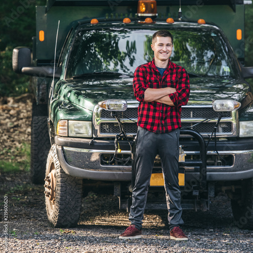 Happy smiling young farmer man standing in front of pickup truck readty to work photo