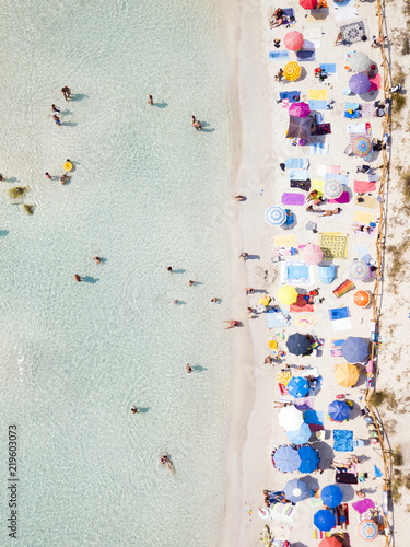 Obraz na płótnie Aerial view of a white beach full of colored beach umbrellas and relaxed people swimming on a clear sea. Cala Brandinchi, Sardinia, Italy. w salonie