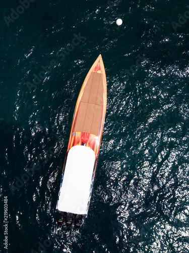 Aerial view of a beautiful orange racing boat sailing on a transparent and turquoise sea. Sardinia, Italy.