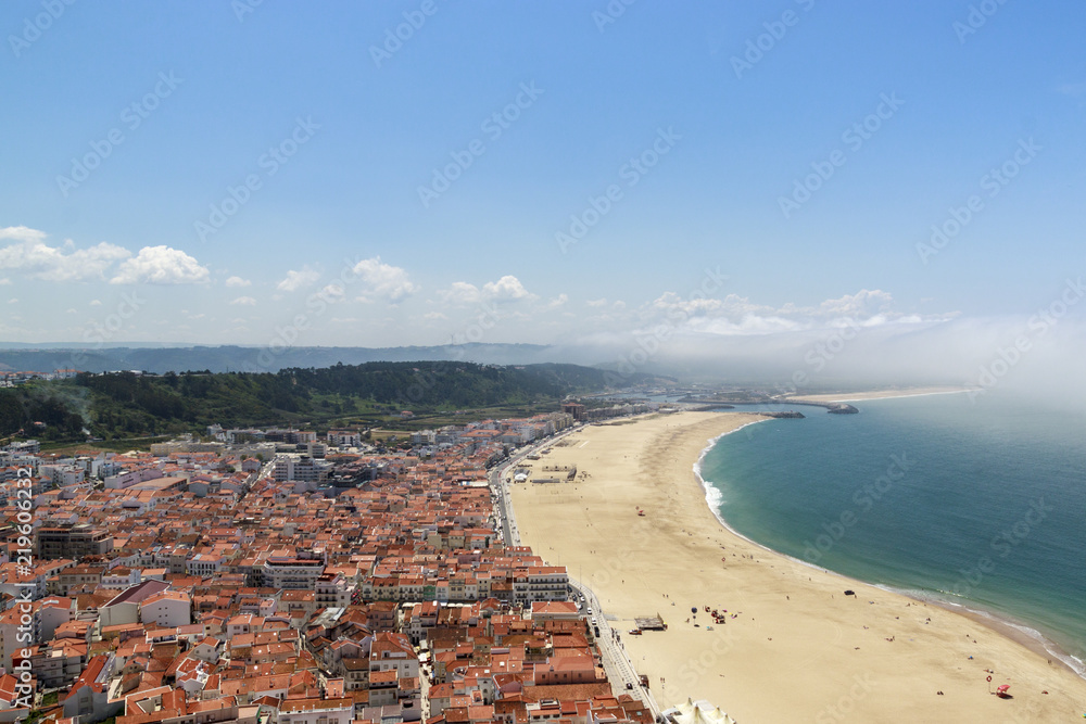 Scenic view of Nazare beach from the funicular. Coastline of Atlantic ocean. Portuguese seaside town on Silver coast. White houses and red tiled roofs Sea landscape of Nazare, Portugal