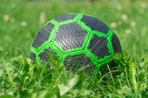 Childrens soccer green ball on a glade with high grass close-up