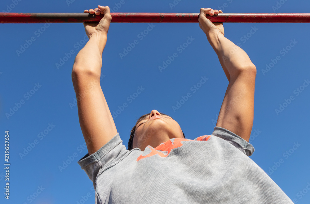 Naklejka premium background. handsome guy in a gray t-shirt (aloha), pulls up on the bar