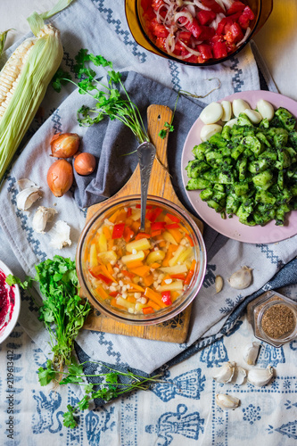 Vegetables broth soup with corn, carrot, red pepper, potato, pumpkin, onion, cabbage, spices and herbs, Green cucumbers salad. Tomato cherry sauce. Vegan vegetarian healthy food lunch or dinner