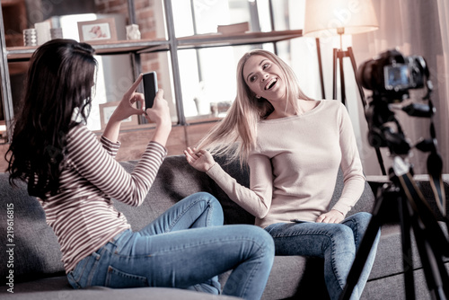 Great photos. Cheerful blond woman smiling while her friends photographing her
