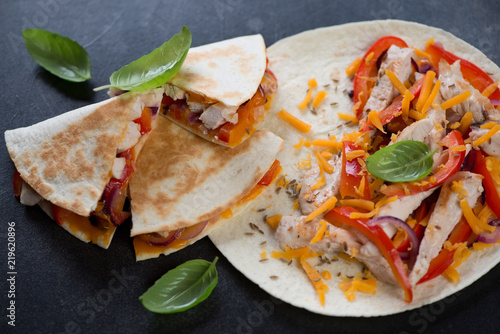 Closeup of quesadilla stuffed with grilled chicken meat, vegetables and cheddar, selective focus