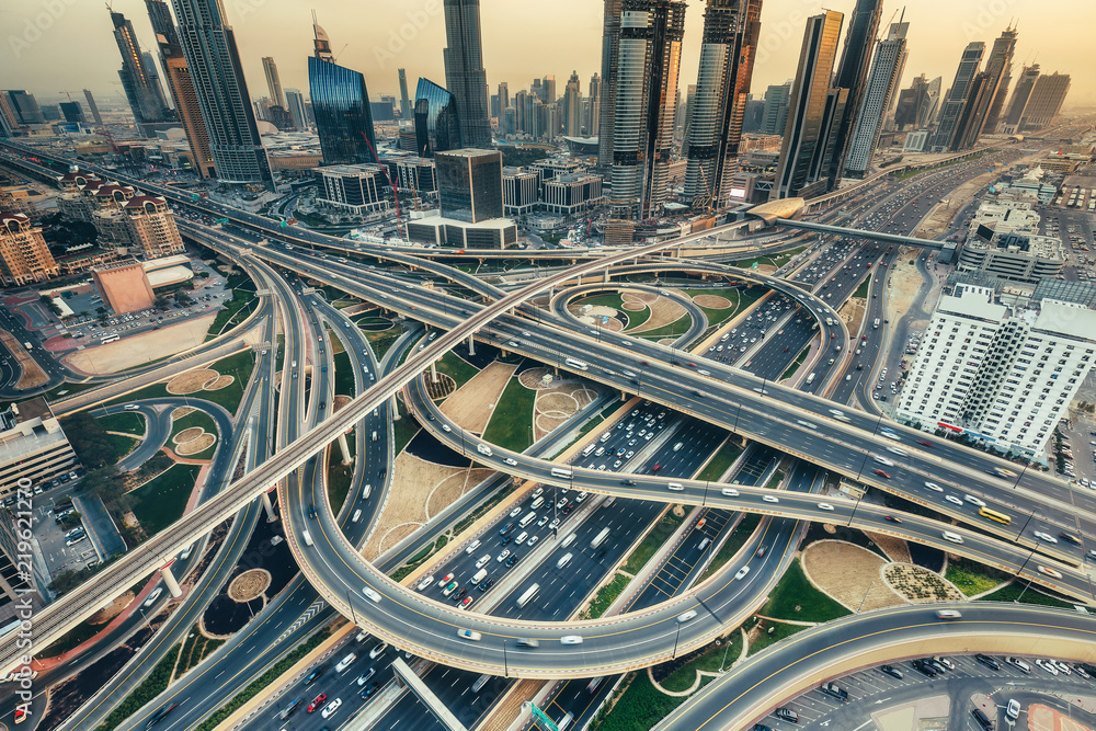 Naklejka premium Widok z lotu ptaka na skrzyżowaniu dużych autostrad w Dubaju, ZEA, o zachodzie słońca. Koncepcja transportu i komunikacji.