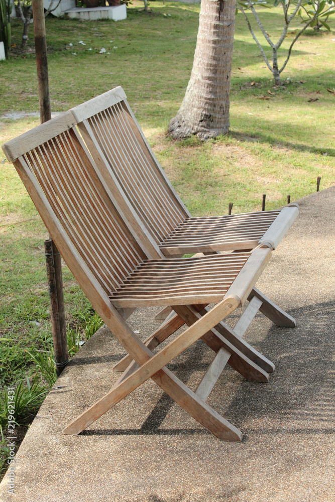 Wooden Bench and chairs near swimming pool in tropical resort and palm tree garden on the beach and sea in Thailand Wooden Bench and chairs near swimming pool in tropical resort and palm tree garden on the beach and sea in Thailand