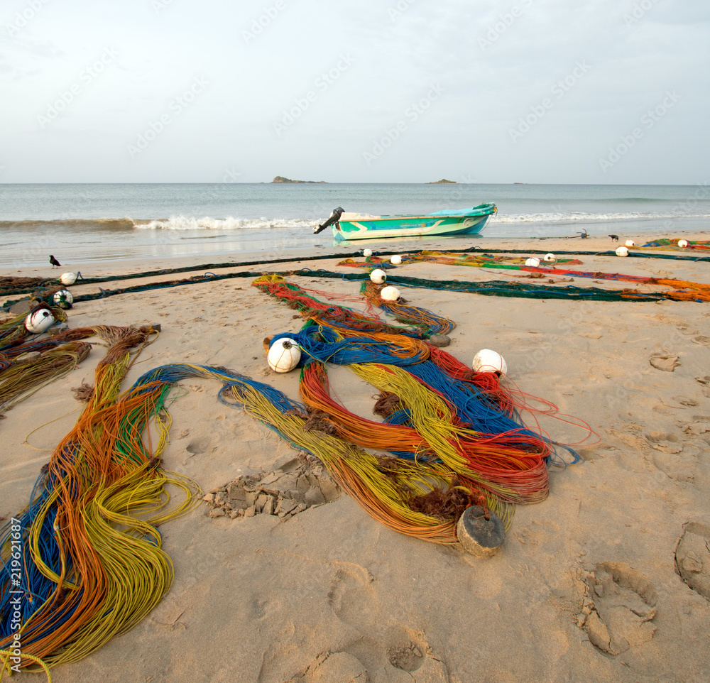 Multi-colored fishing nets drying in the sun next to small fishing boat on  Nilaveli beach in Trincomalee Sri Lanka Asia Stock Photo