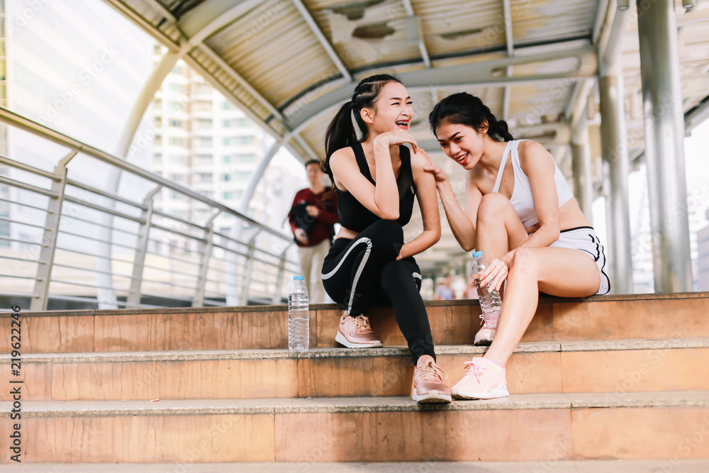 Group of sporty female friends sitting on the steps of the city .They enjoy having fun after a workout during a morning exercise.