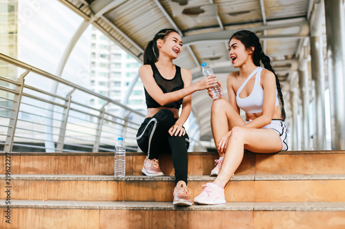 Group of sporty female friends sitting on the steps of the city .They enjoy having fun after a workout during a morning exercise.