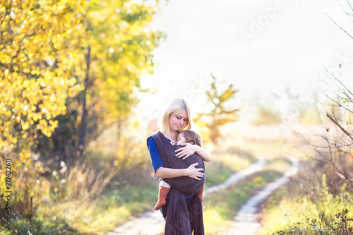 Young mother carrying her baby in a shawl sling. Shot on location with natural light. Autumn season