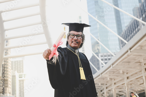 Happy senior adult man in a hat with his gown on graduation day.