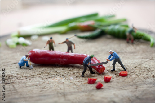 Miniature figure  Workers are chopping red pepper with saw .