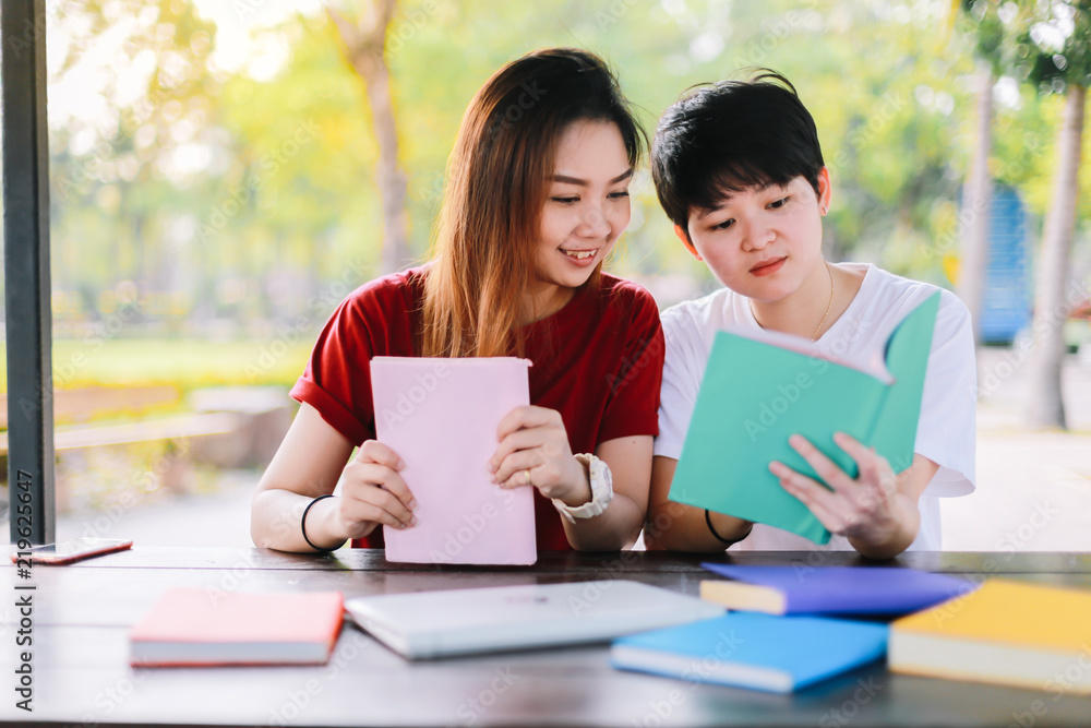 Education concept -Two brest friends who are happy reading books together on a wooden desk in a university. Education concept -Two brest friends who are happy reading books together on a wooden desk in a university.