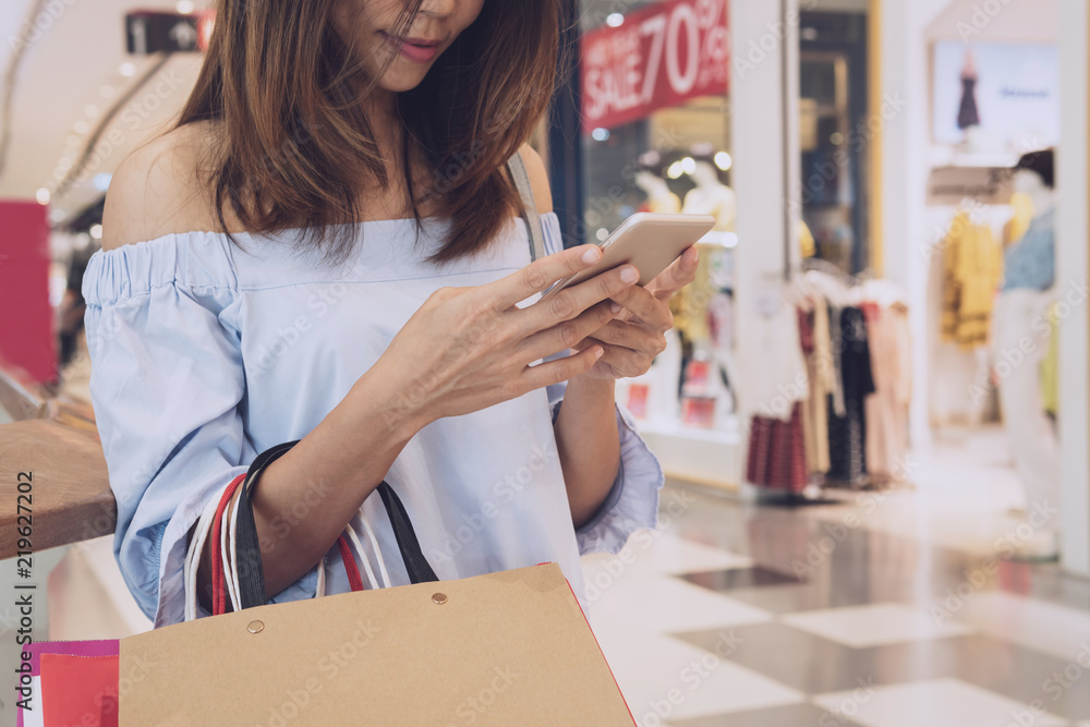 Young woman with shopping bags using smart phone and shopping in the mall, Woman lifestyle concept