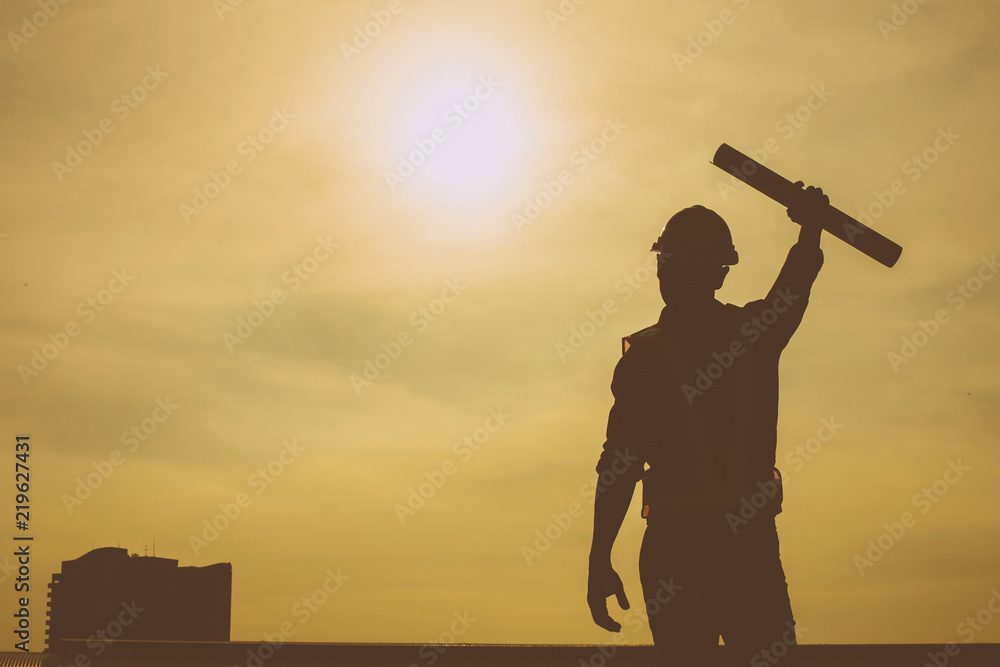 Silhouette of engineer and confident working closely and successfull,He standing outdoors with evening sun light in the background. Silhouette of engineer and confident working closely and successfull,He standing outdoors with evening sun light in the background.