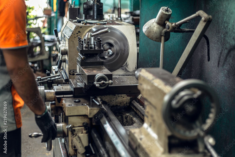 LATHE MACHIN, Worker in uniform operating in manual lathe in metal industry factory. LATHE MACHIN, Worker in uniform operating in manual lathe in metal industry factory.