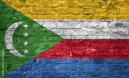 Flag of Comoros over an old brick wall background, surface