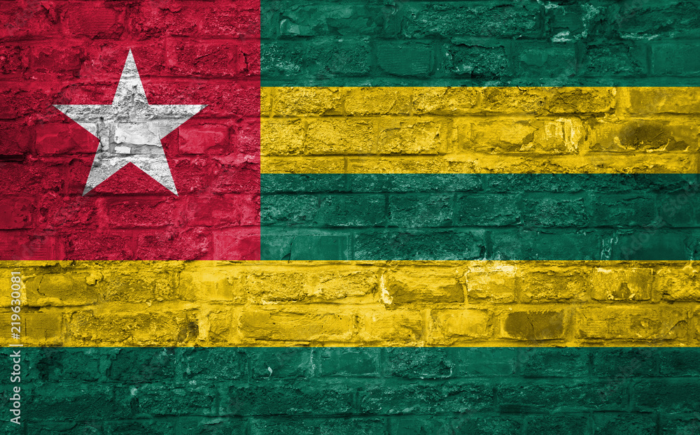 Flag of Togo over an old brick wall background, surface