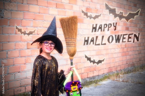 portrait of witch girl with broom and cauld outside, halloween concept photo