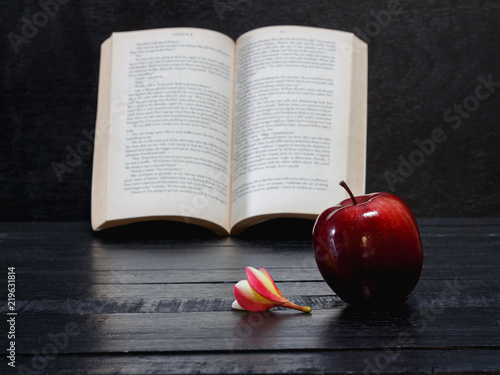 frangipani flower and red apple and book on wooden desk