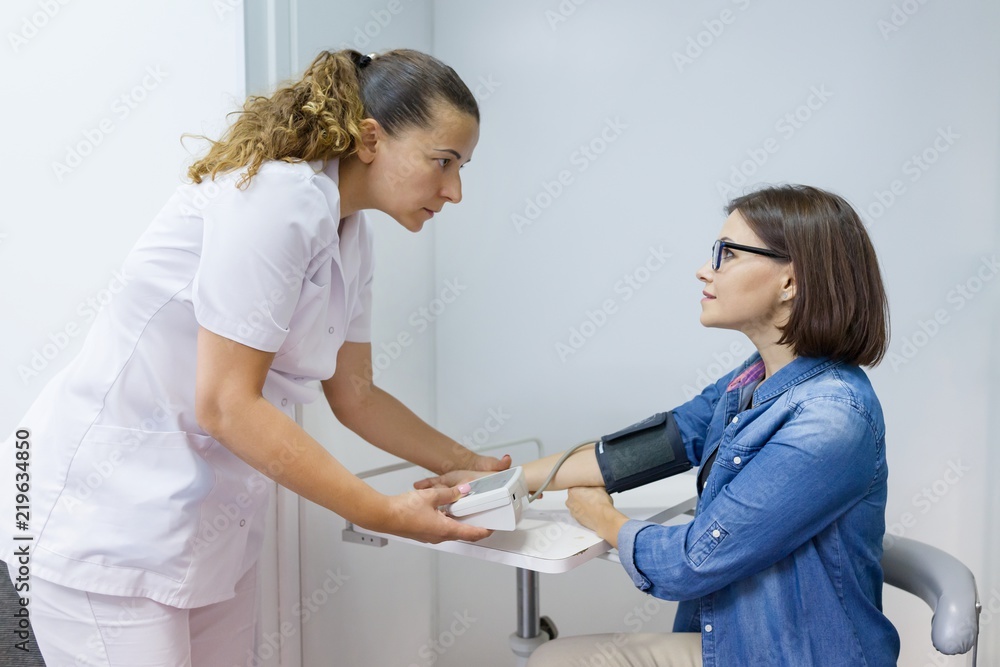 Obraz premium Nurse taking female patient's blood pressure in office