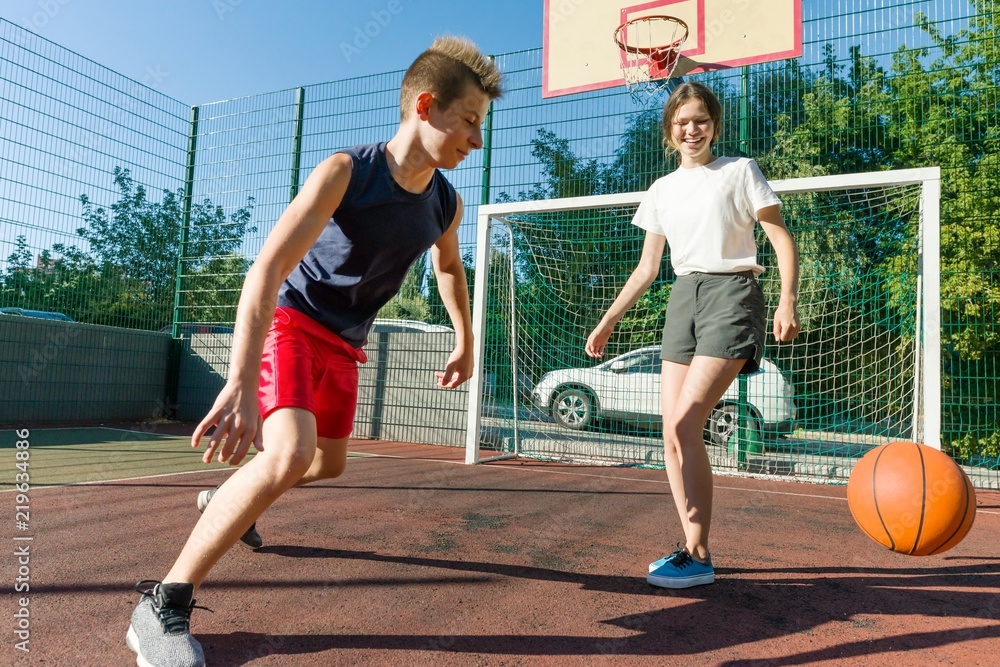 Obraz premium Streetball basketball game with two players, teenagers girl and boy, morning on basketball court