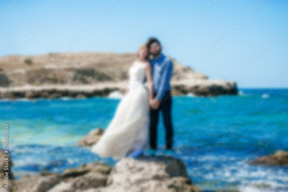 Blurred photo of a couple of newlyweds on a beach near the sea.