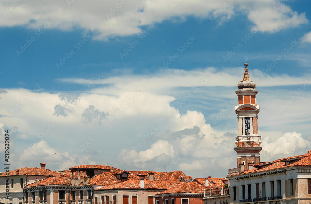 Church of the Holy Apostles of Christ baroque bell tower, built between 17th and 18th century, rise above Venice historic center old buildings among clouds