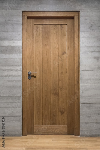 Modern quality wooden door in contemporary interior, Solid oak door with stainless steel handle set in concrete wall