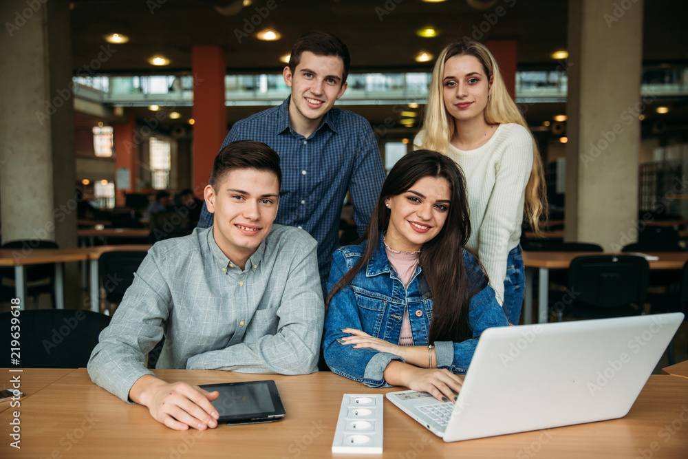 Group of college students studying in the school library, a girl and a boy are using a laptop and connecting to internet Group of college students studying in the school library, a girl and a boy are using a laptop and connecting to internet