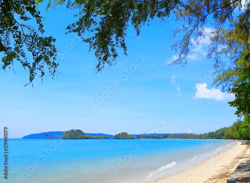 The beach of Southern Thailand. Small wave hit the shore. The sea is blue and the sky is clear, so you can see the small islands off the coast.